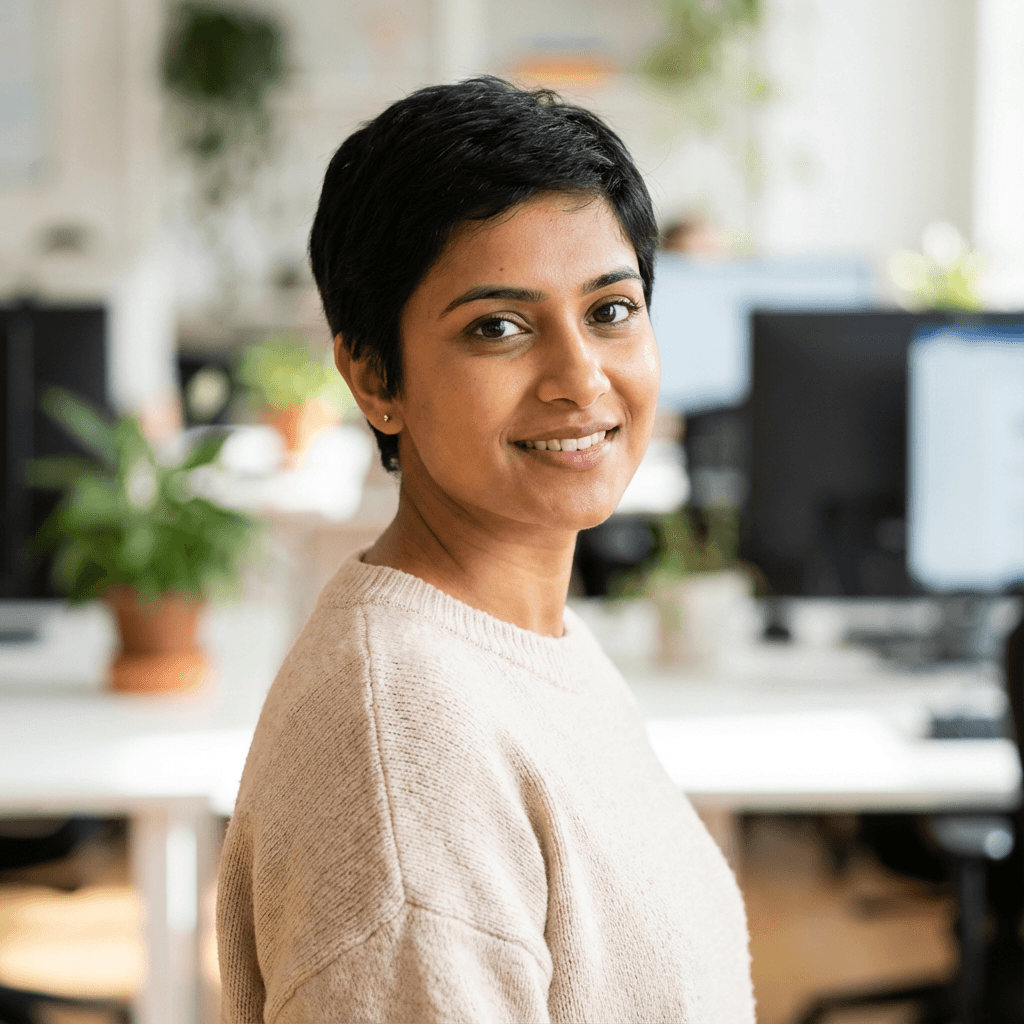 Anita Paul, a South Asian woman in her late 30s, smiling in a bright office